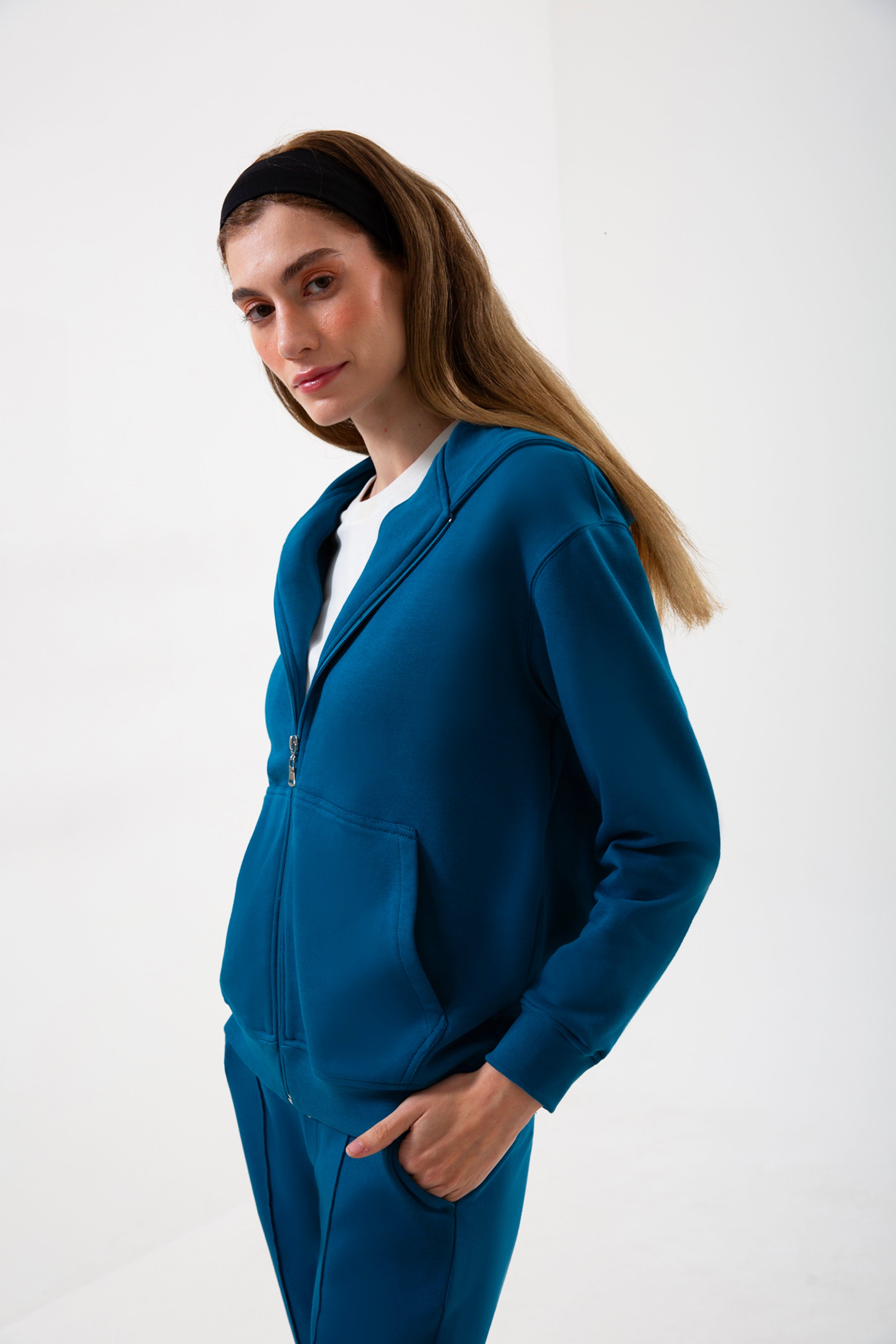 Günlük stile zahmetsiz bir uyum sağlayan bu petrol mavisi kapüşonlu sweatshirt, yumuşak dokusu ve rahat kesimiyle her mevsimde konfor sunar. Minimal çizgilere sahip regular fit formu, şehir hayatından ev rahatlığına kadar her ortamda doğal bir şıklık yaratır.
Fermuarlı tasarımı sayesinde katmanlı kombinlere kolayca uyum sağlayan bu kadın sweatshirt; nefes alan yapısı, sade görünümü ve işlevsel kapüşonuyla gün boyu sıcak ve konforlu bir kullanım sunar.